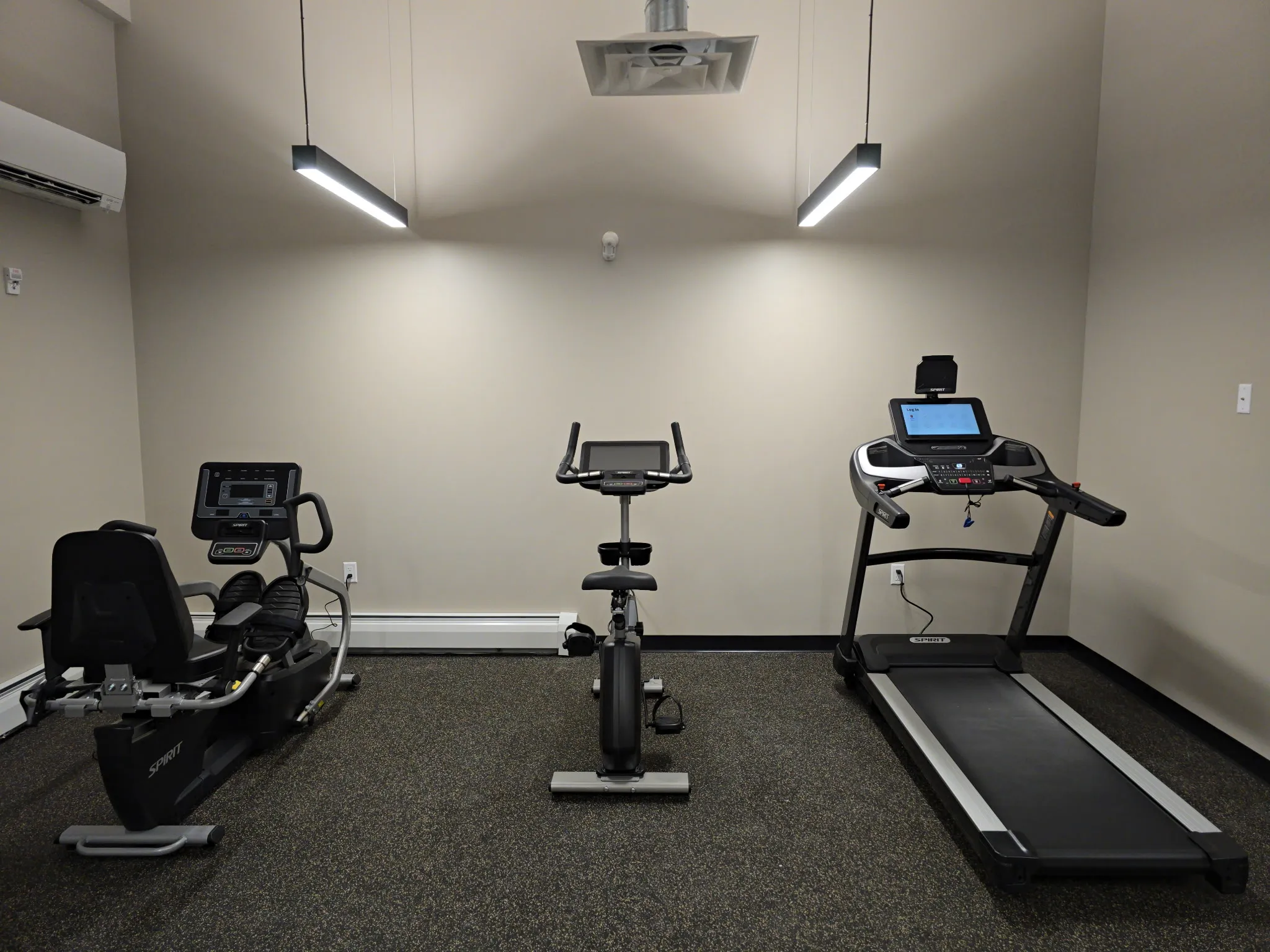 Home fitness equipment installed in a Westbrook, Maine amenity room: recumbent bike, upright bike, and treadmill.
