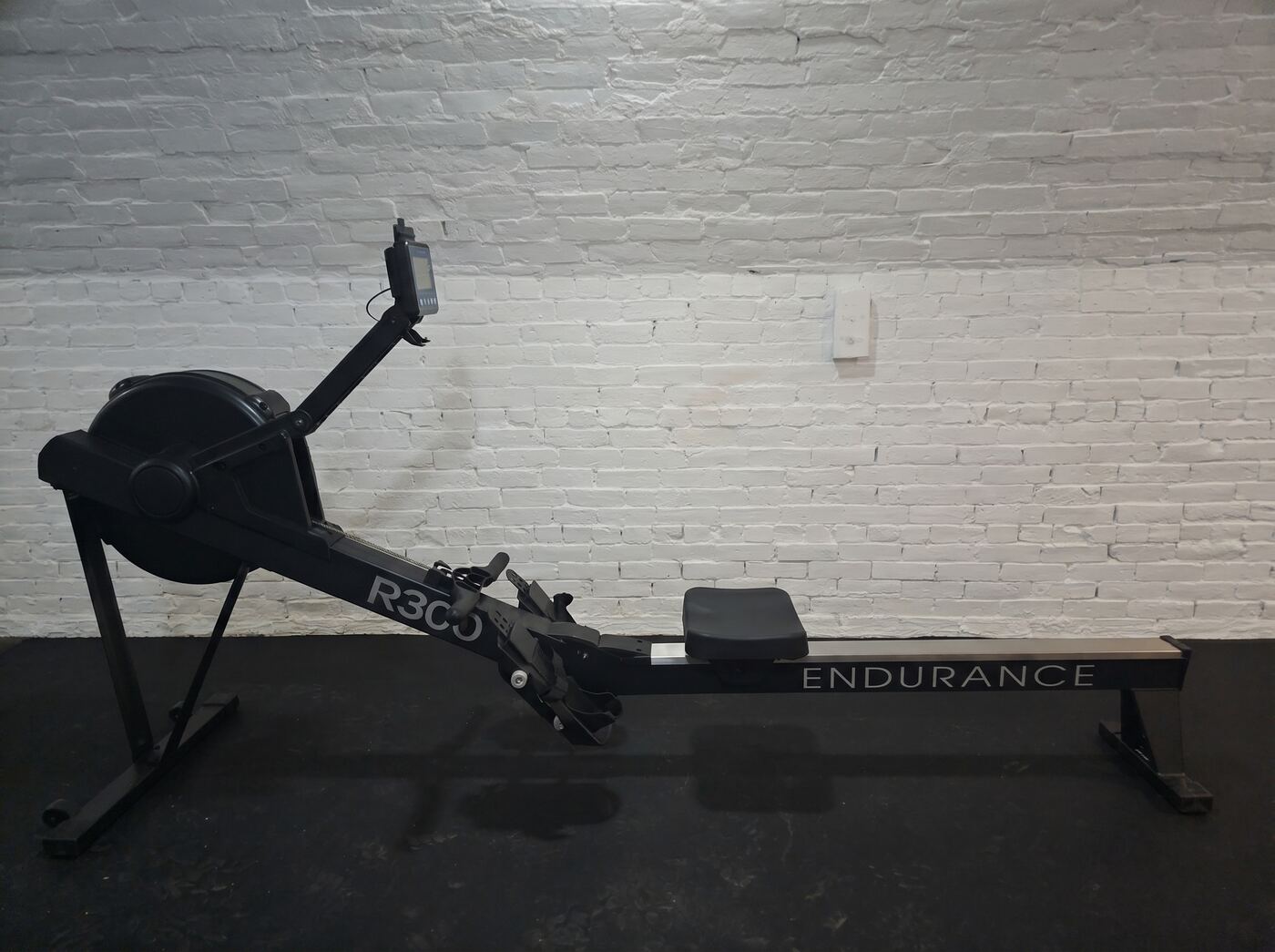 Endurance R300 rower installed against a painted-brick wall
